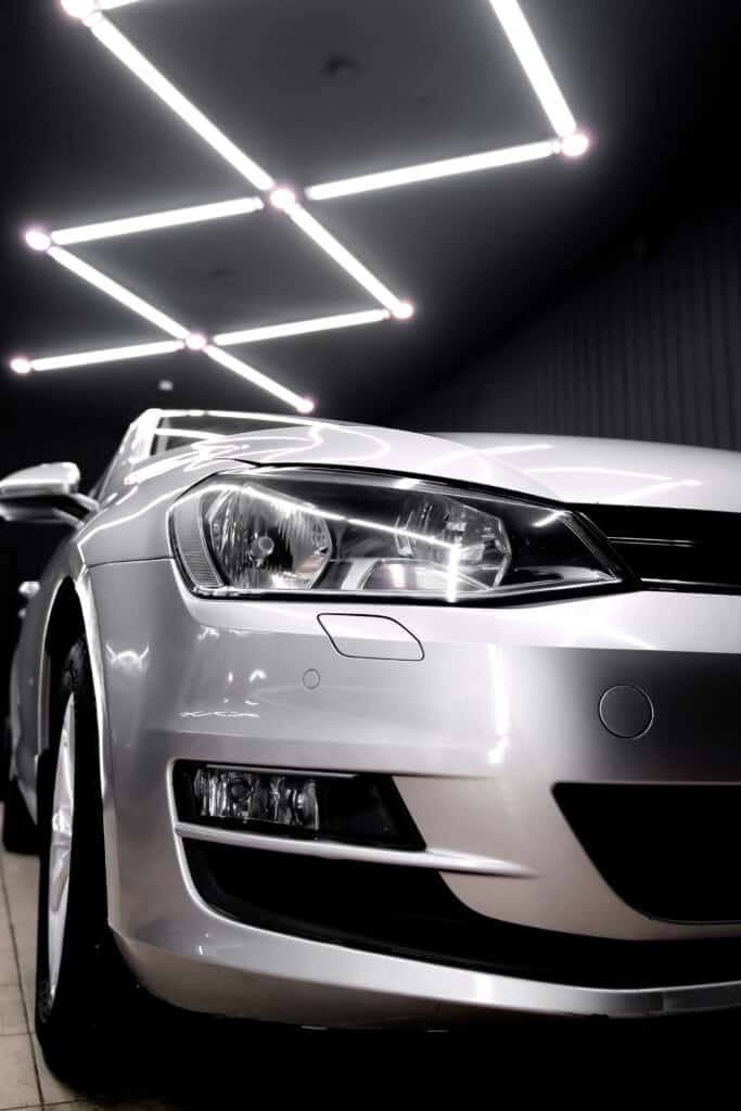 Gros plan avant d'une voiture grise sous éclairage LED de détail automobile, reflets intenses sur la carrosserie.